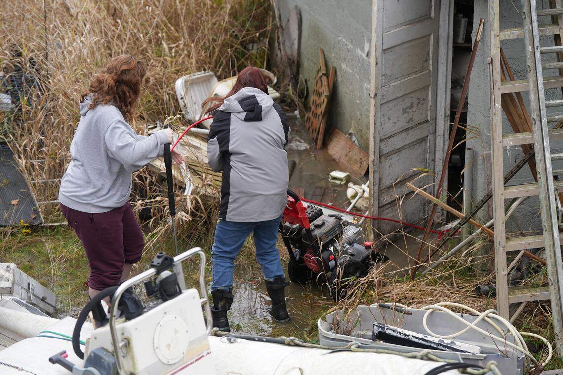 Makela Hatch (left) and Laura Buckley help clear valuable items out of Buckley’s brother’s garage in Ferndale, which was already completely flooded on December 11, 2025. Floodwaters were expected to continue to rise.