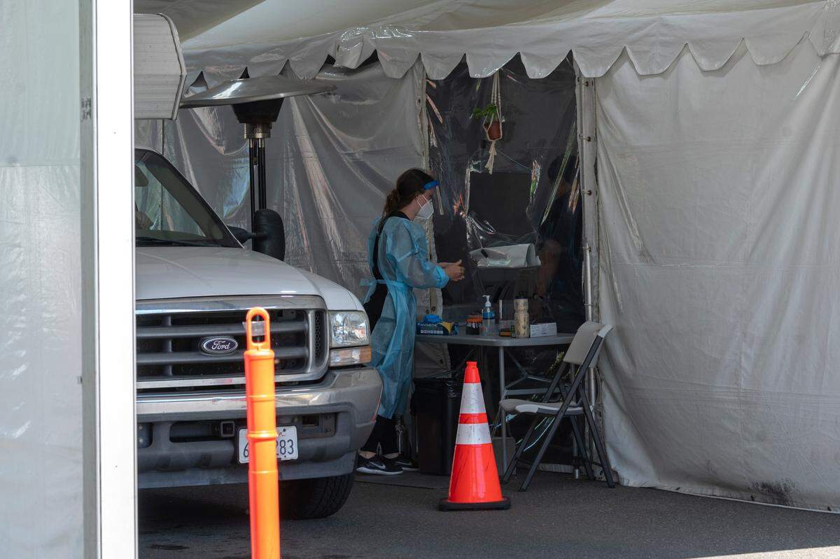 A worker prepares to test someone for COVID-19 at a testing center in the parking area of Bellingham International Airport on Wednesday, Aug. 11, in Bellingham.
