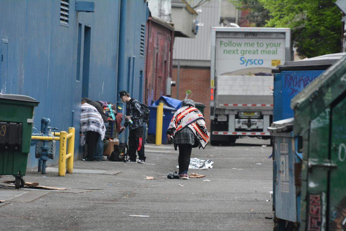 Several people are shown in the alley west of Railroad Avenue near West Holly Street in downtown Bellingham, Wash., on Wednesday, April 23, 2026.