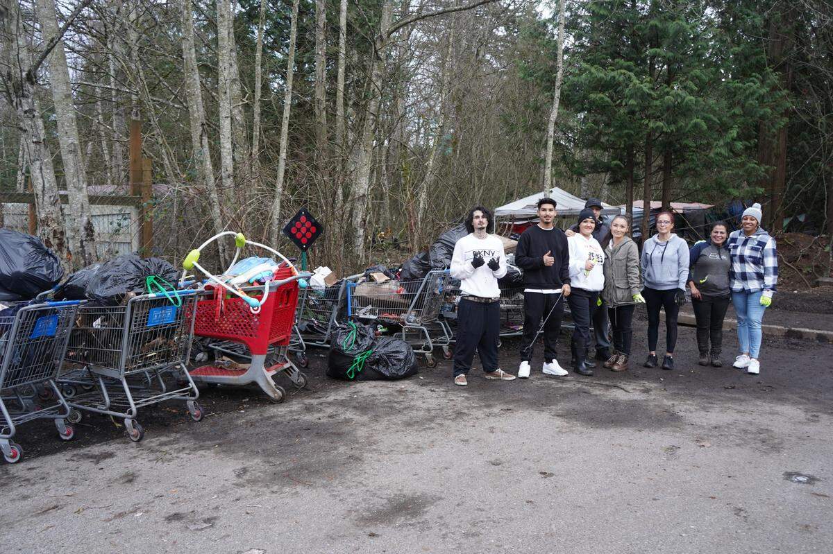 Hanah Warthan stands with her family, volunteers and people experiencing homelessness near the encampment behind Walmart on Dec. 29, 2023, in Bellingham, Wash. The group cleaned up about 15 shopping carts full of garbage from the encampment.