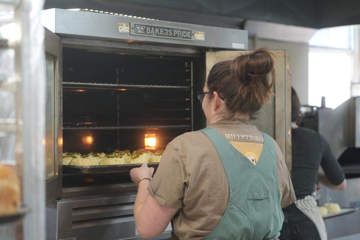 Clara Dwyer puts jalapeño cheddar bagels in the oven to bake at Millet Bakery.