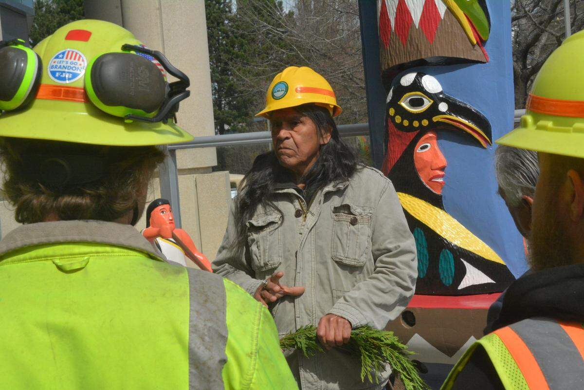 Ralph Bennett, center, one of two people who restored a Lummi Nation story pole, explains the pole’s significance to to Whatcom County workers who installed it at the County Courthouse in downtown Bellingham on Thursday, April 13. The story pole, which depicts the tribal chief, his brother and two early European settlers, was created in 1952 to mark the event’s centennial. It was removed for restoration after it was vandalized in early 2021.