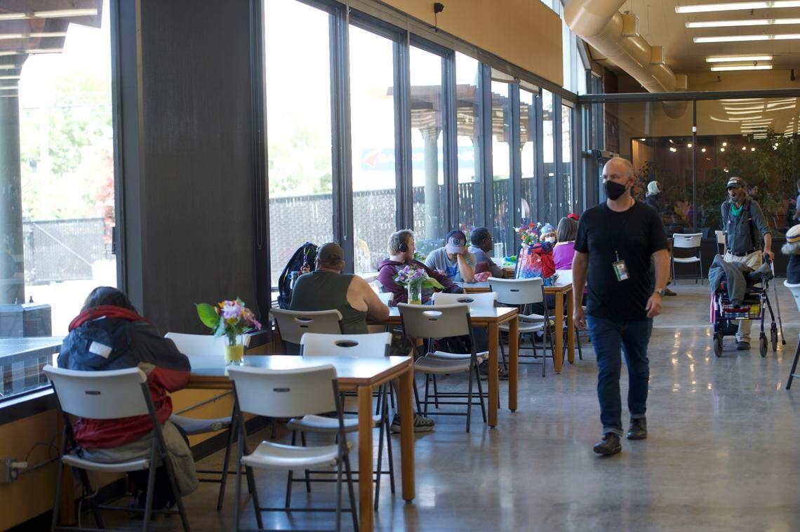 Lighthouse Mission Ministries Director Hans Erchinger-Davis walks by guests at tables at the new Base Camp temporary shelter for homeless people at the former Bellingham Public Market on Friday, July 17, in Bellingham.