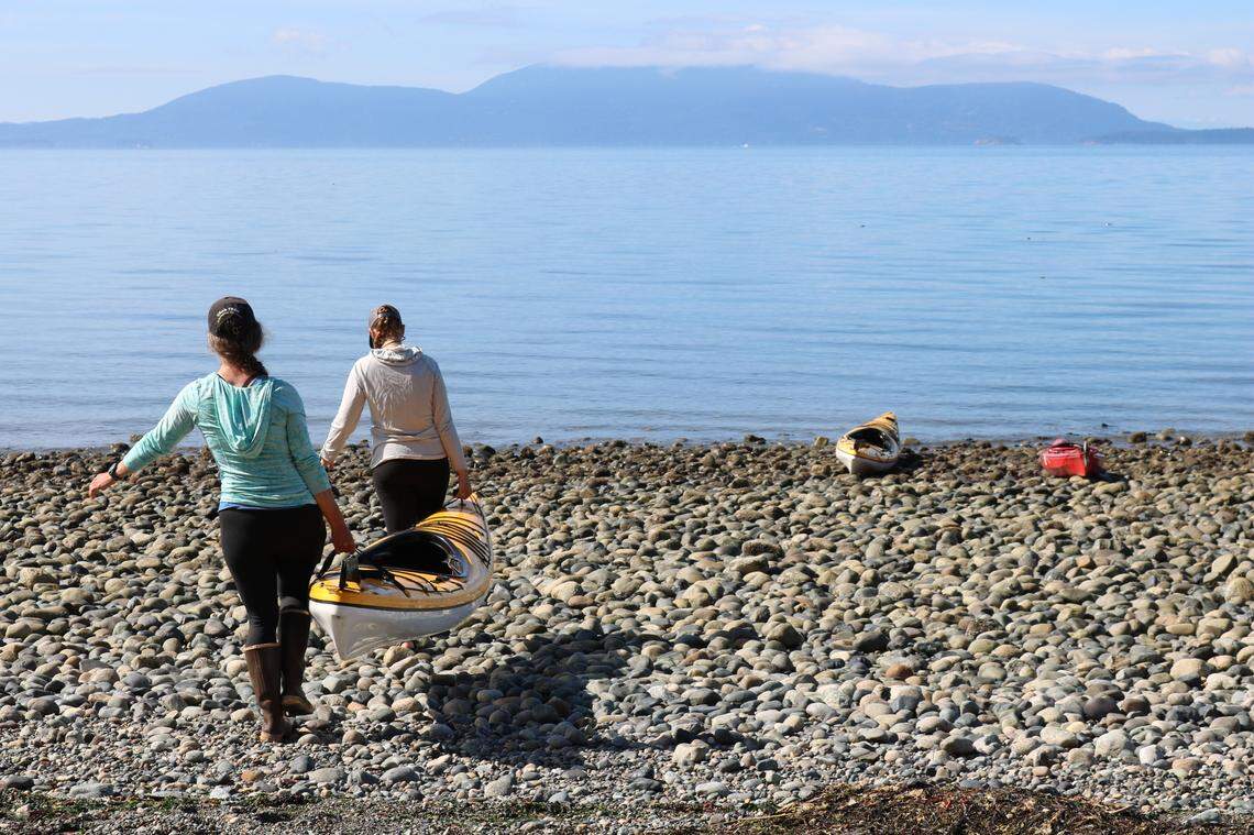 Kelp monitoring volunteers Eleanor Hines and Brooke Friesen carry a kayak down to the shore at Cherry Point Aquatic Reserve in Whatcom County on Tuesday, Aug. 10.