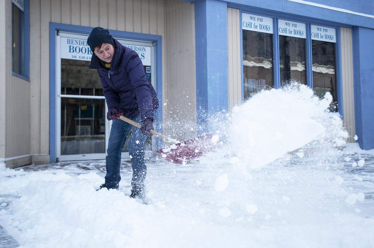 Gina Gabl, a Henderson Books employee, shovels snow off of the sidewalk in front of the storefront in downtown Bellingham, Wash., on Monday, Feb. 11, 2019.