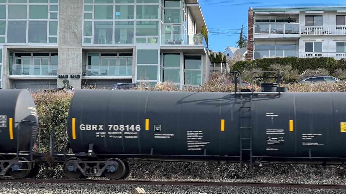A BNSF freight train carrying oil tankers rolls past apartments along the waterfront in Boulevard Park in Bellingham in March.