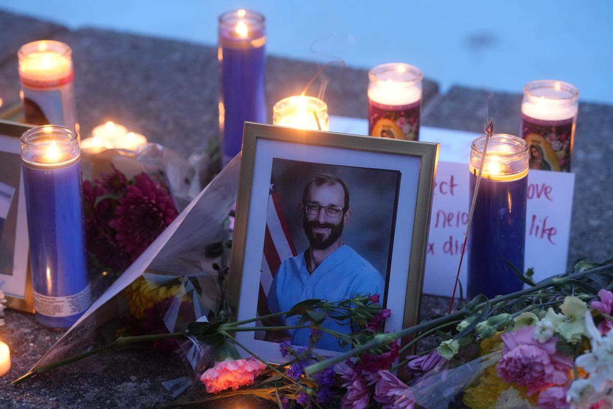 A framed image of Alex Pretti, a Minneapolis nurse who was shot and killed by ICE agents, is surrounded by flowers and candles at an anti-ICE vigil at Western Washington University.