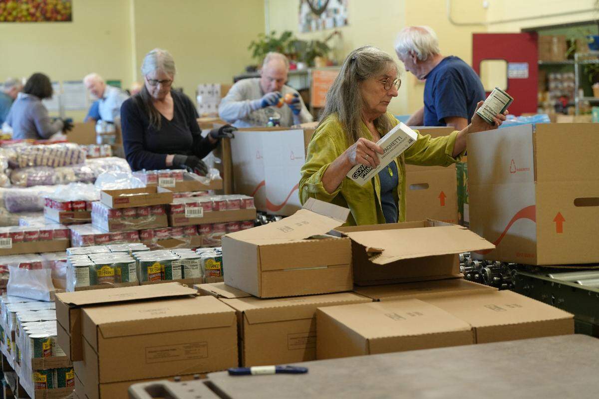 Volunteers package boxes with staple food items at the Bellingham Food Bank.