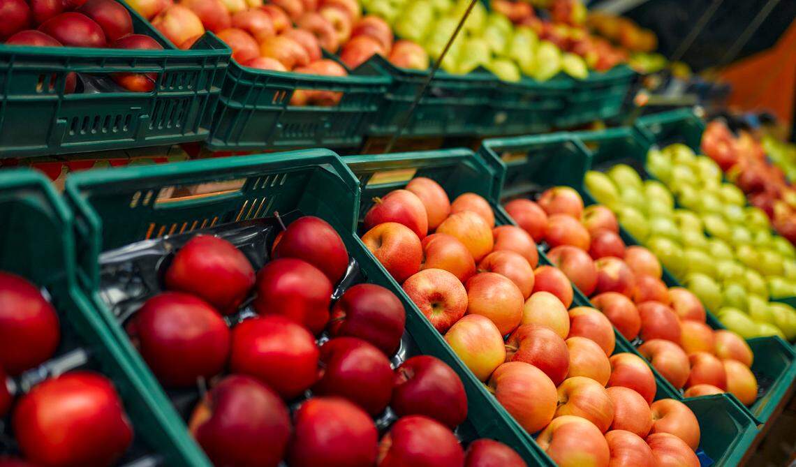 Crates of fresh fruit and apples inside a grocery store.