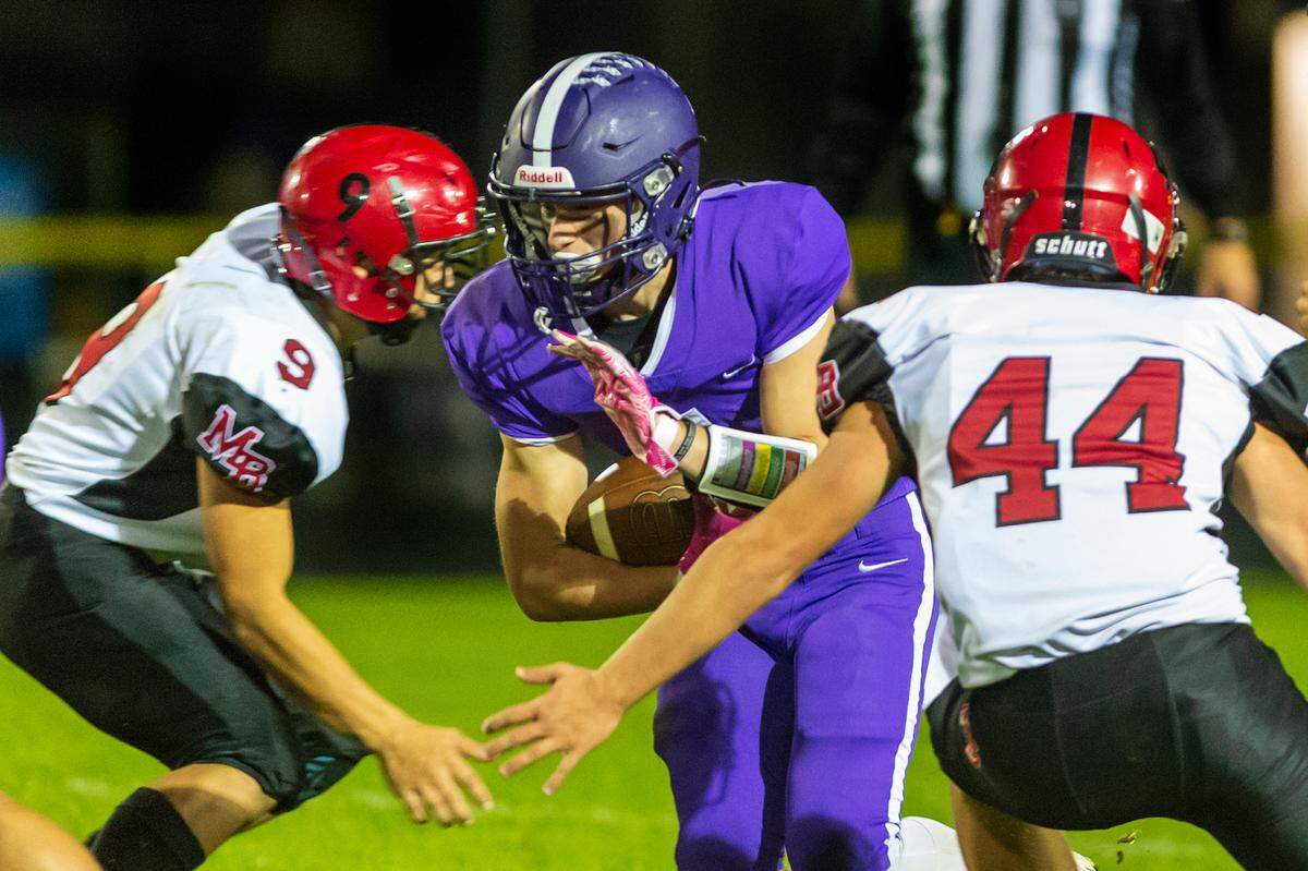 Mount Baker defenders Marques George (9), left, and Brady West (44) move in to stop Nooksack Valley running back Jordan Silva (4) at the line of scrimmage during the second quarter on Friday evening Oct. 8, 2021, at Nooksack Valley High School.