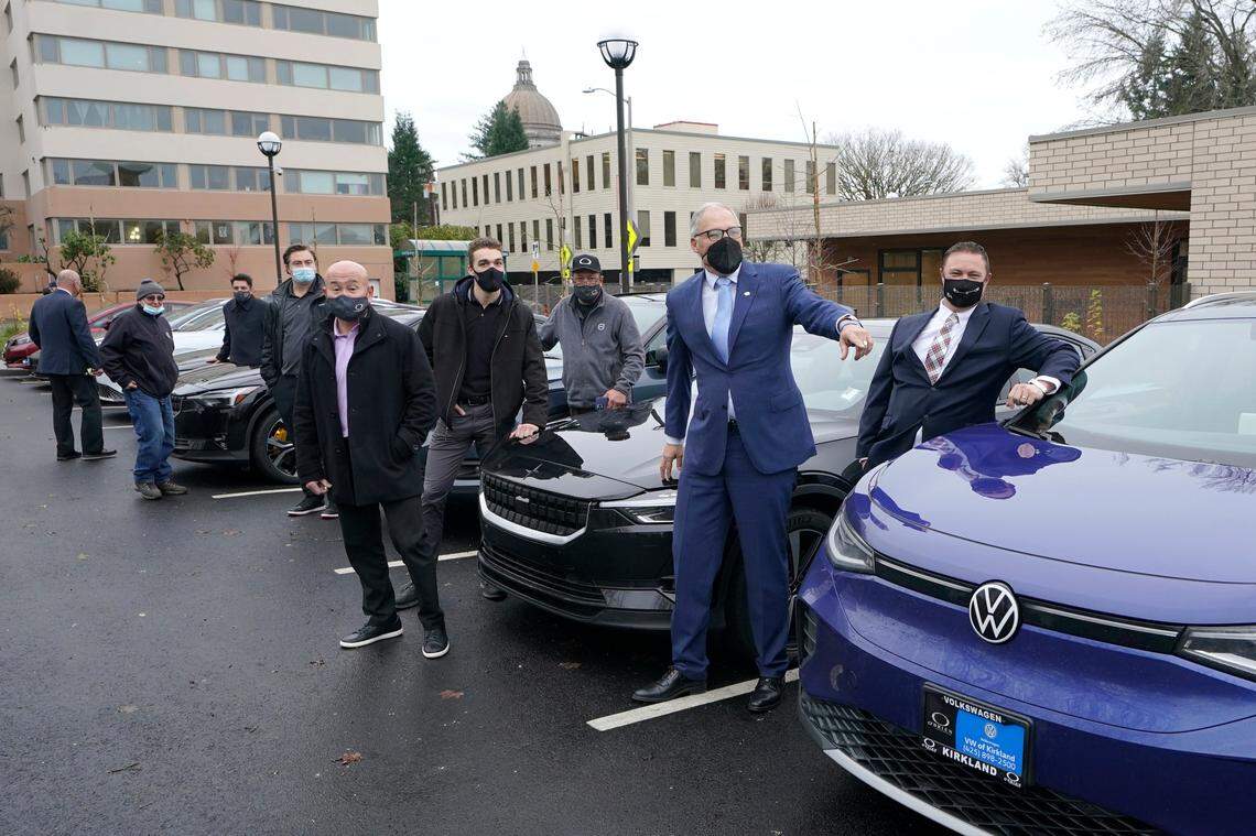 Washington Gov. Jay Inslee, second from right, poses for a photo, Monday, Dec. 13, with car dealership representatives who drive electric vehicles to a news conference in Olympia. Inslee announced several climate-related proposals for the 2022 legislative session, including a plan to offer rebates on the purchase of new and used electric vehicles for qualified buyers.