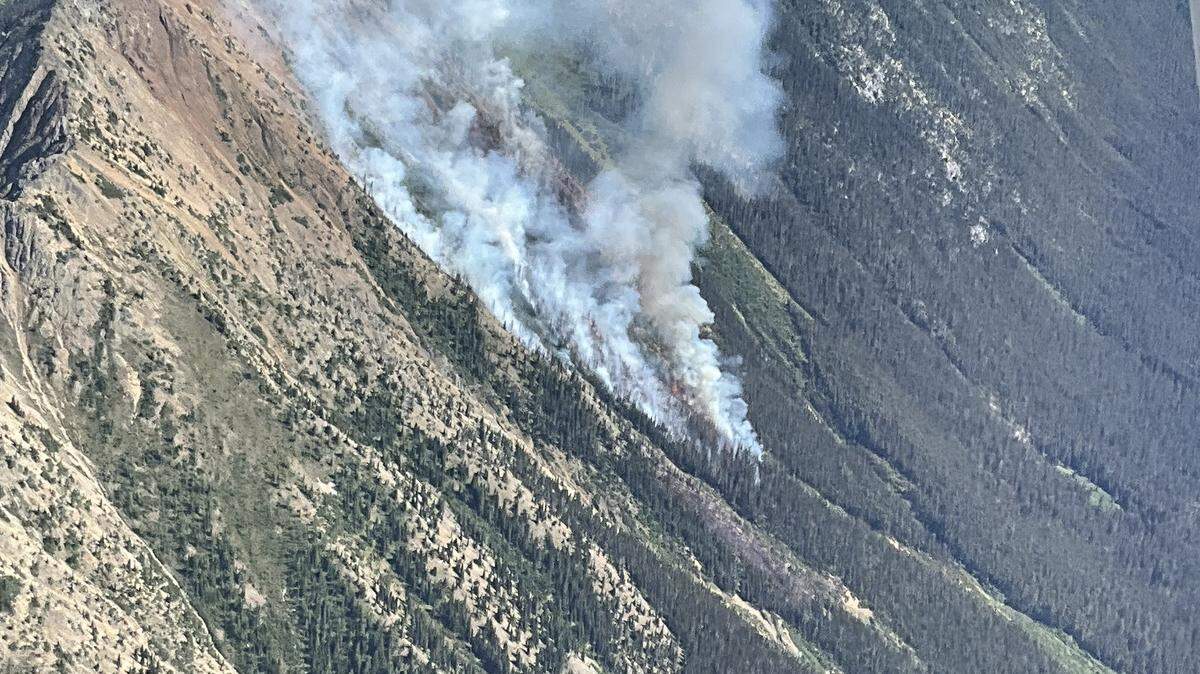 Smoke rises from the East Creek Fire burning in steep and inaccessible avalanche chutes in the Methow Valley Ranger District on July 29, 2025.