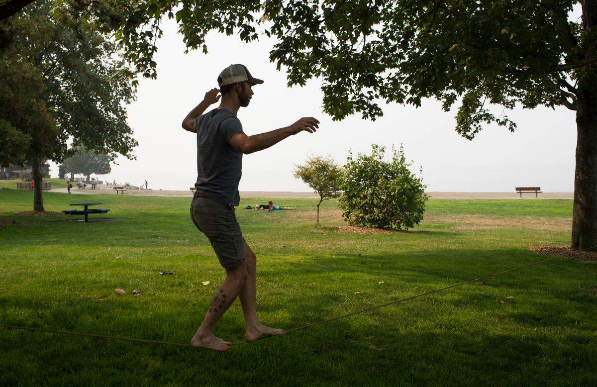 Gaar Lousman walks on a slackline at Boulevard Park on Tuesday in Bellingham. Lousman said he needed to get outside despite the wildfire smoke.