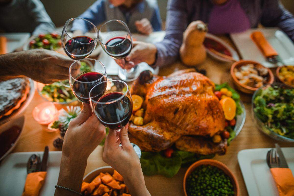 Group of people toasting with wine during Thanksgiving dinner at dining table. Thanksgiving stock photo.