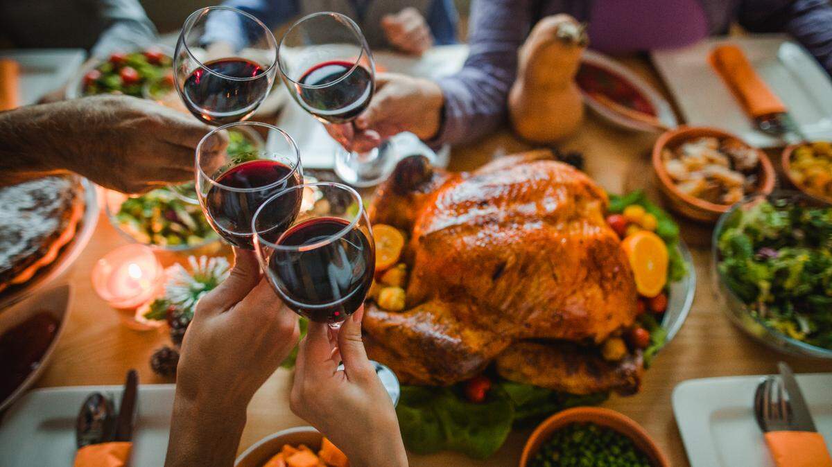 A family toasting with wine around a Thanksgiving dinner table.