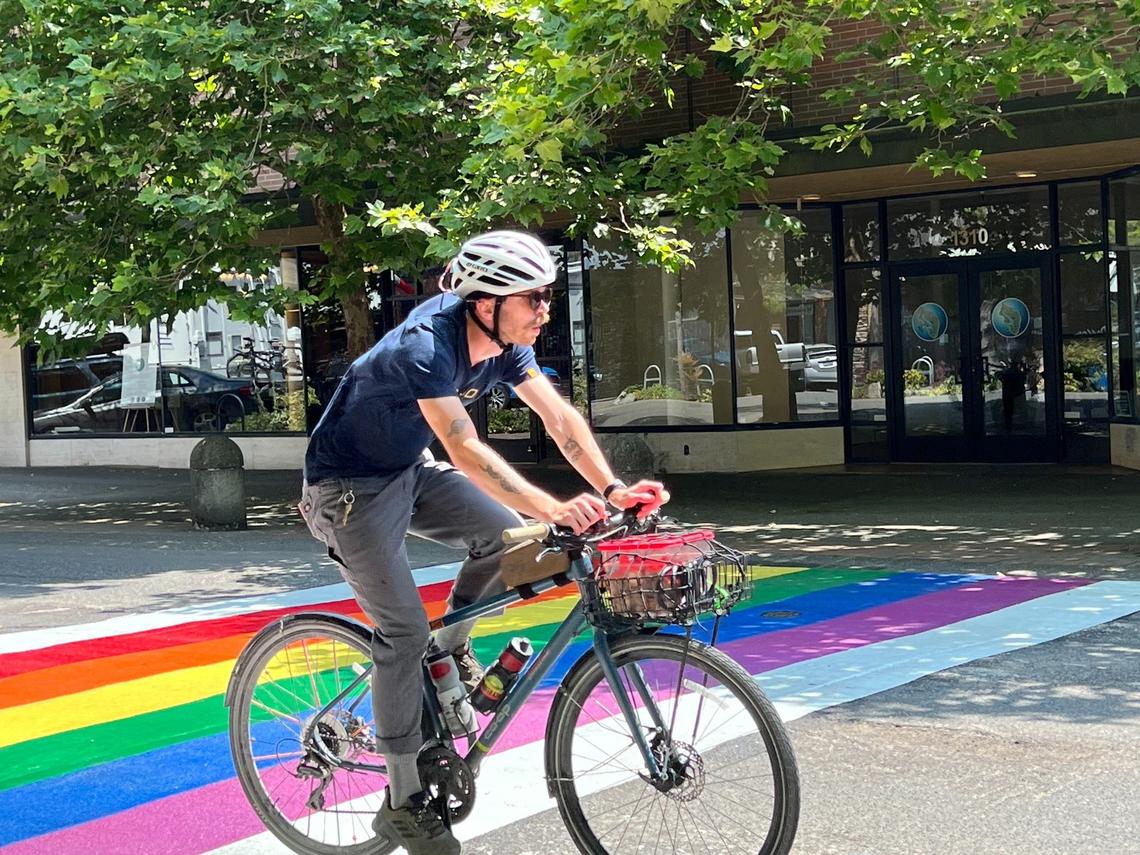 A bicycle rider heads south on Cornwall Avenue past the new Pride crosswalk in downtown Bellingham, Wash., on Friday, July 7, 2023.