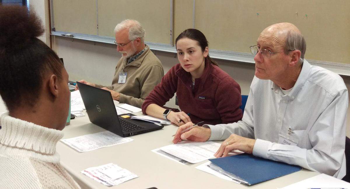 Ashley Ryles, left, whose wallet was stolen at a Greyhound bus station in Louisiana, gets help from Access ID Project volunteers Stephanie Clarke and Doug Bulthuis at the Bellingham Public Library on Dec. 1.