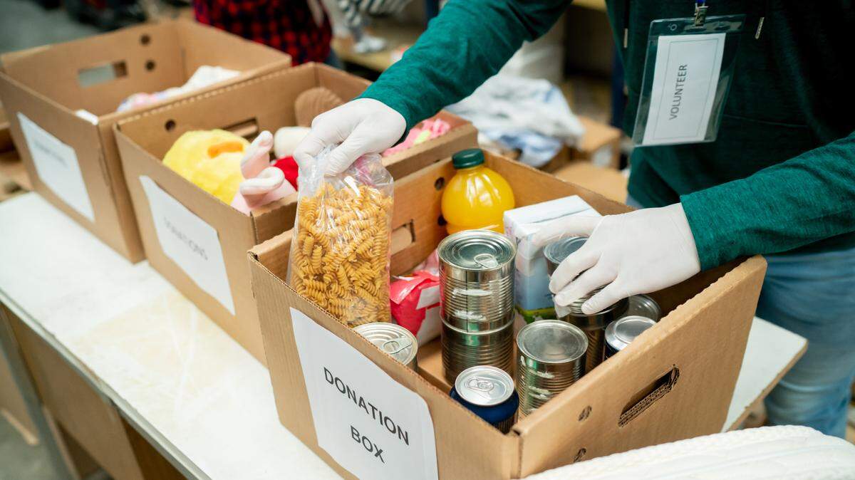 Volunteers wearing protective gloves organize food drive donations.