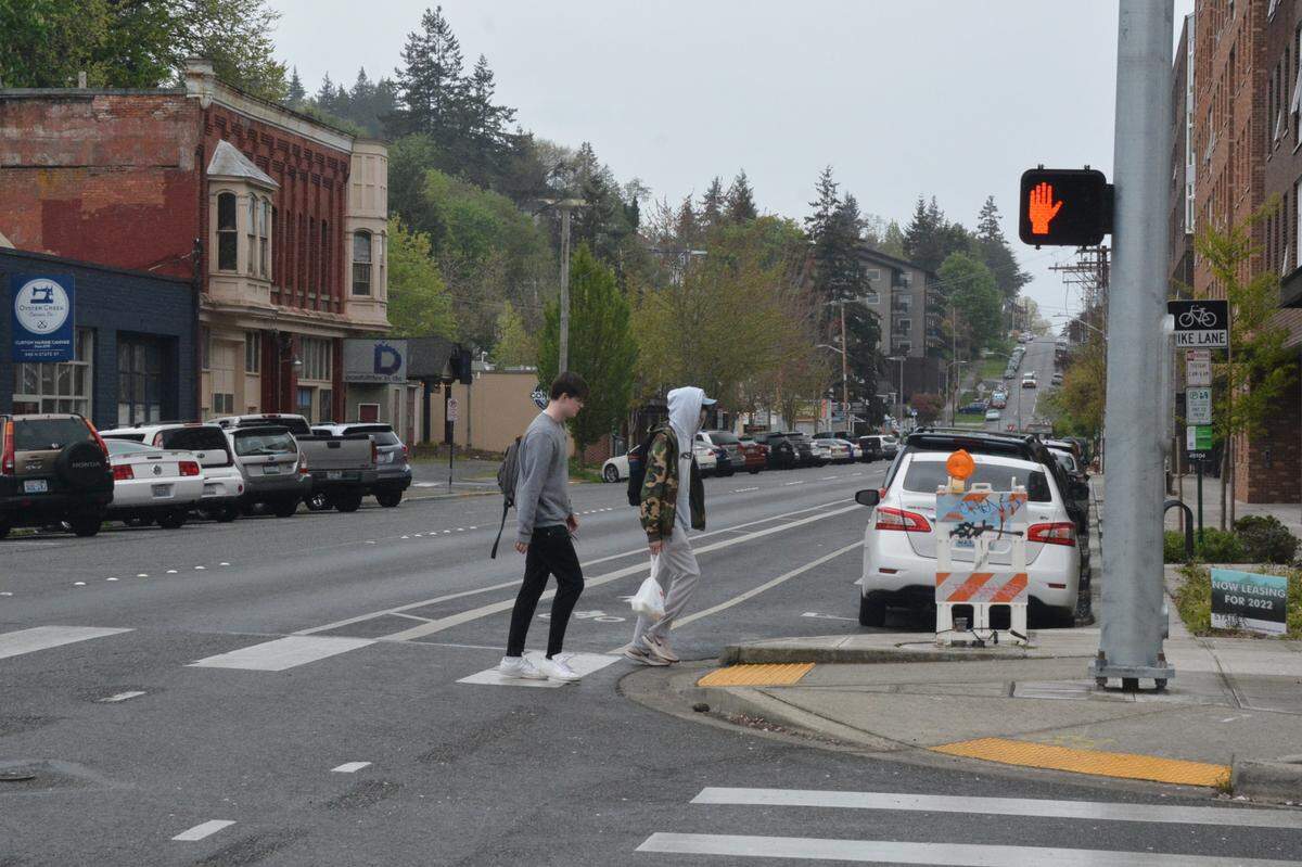 Pedestrians cross North State Street at East Laurel Street in an area of downtown Bellingham, Wash., that offers few shade trees on Friday, May 6, 2022. According to a recent city report, the downtown area had the least tree canopy of any area of the city.