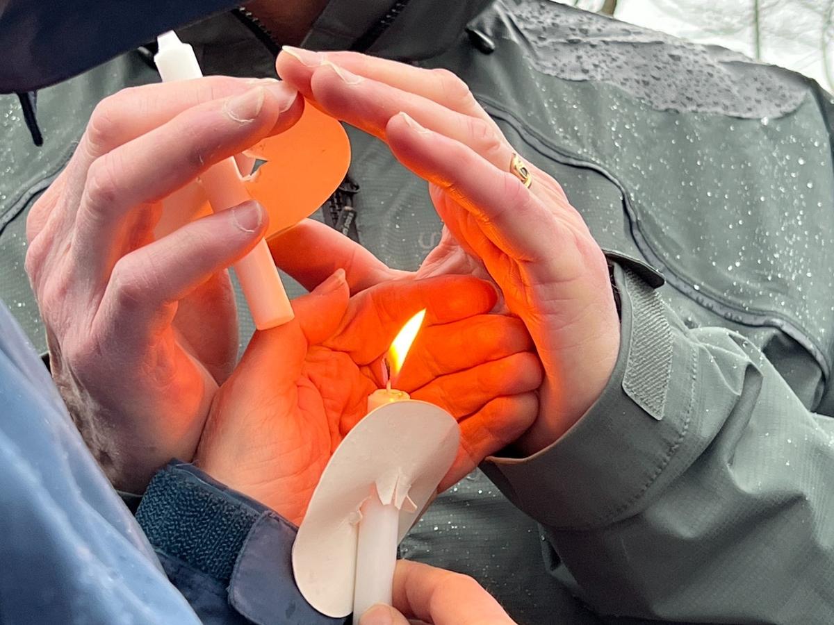 Participants struggle to keep a candle lighted amid wind and rain.