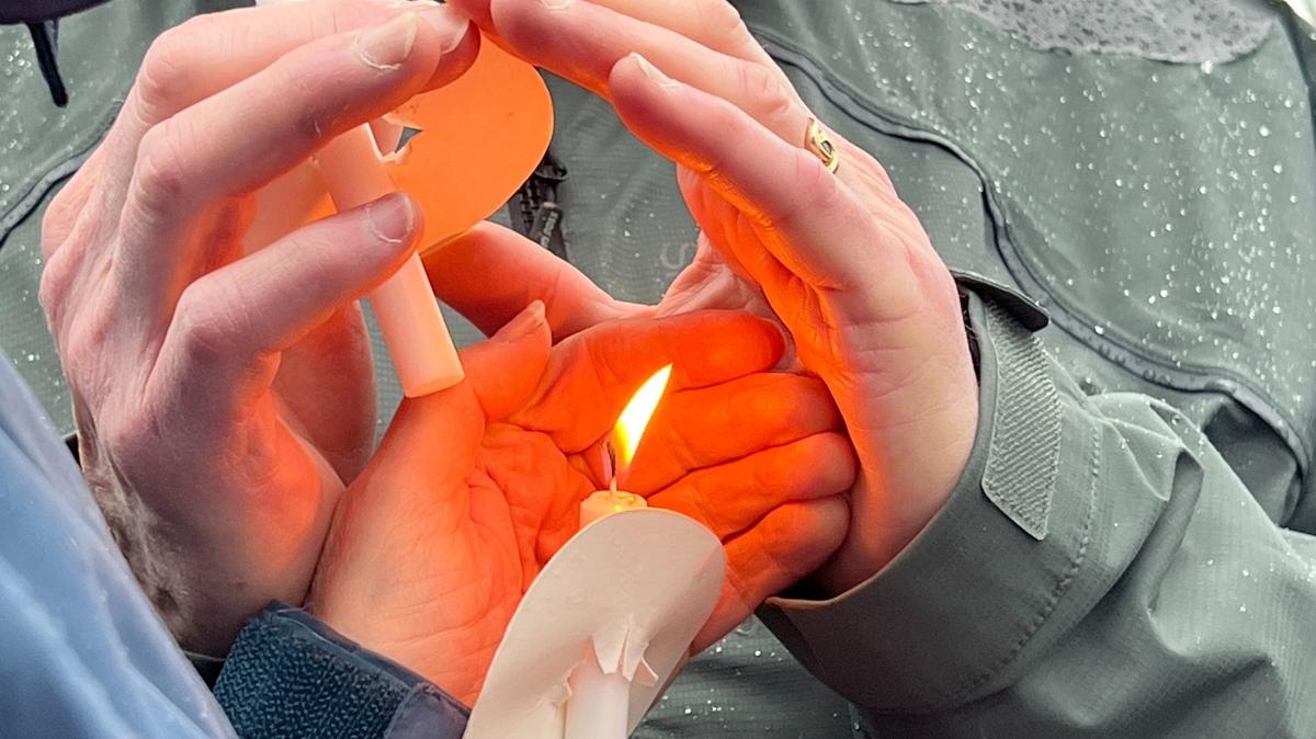Participants struggle to keep a candle lighted amid wind and rain as about 100 people gathered to honor National Homeless Persons Remembrance Day at City Hall plaza in Bellingham on Dec. 21.