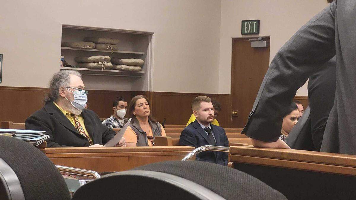 Austin Michael Case, 23, of Ferndale, (center) sits in a court pew at his arraignment Friday, July 21, in Whatcom County Superior Court in Bellingham, Wash. Case is accused of using his position as a law enforcement officer to threaten, blackmail and sexually assault two women.