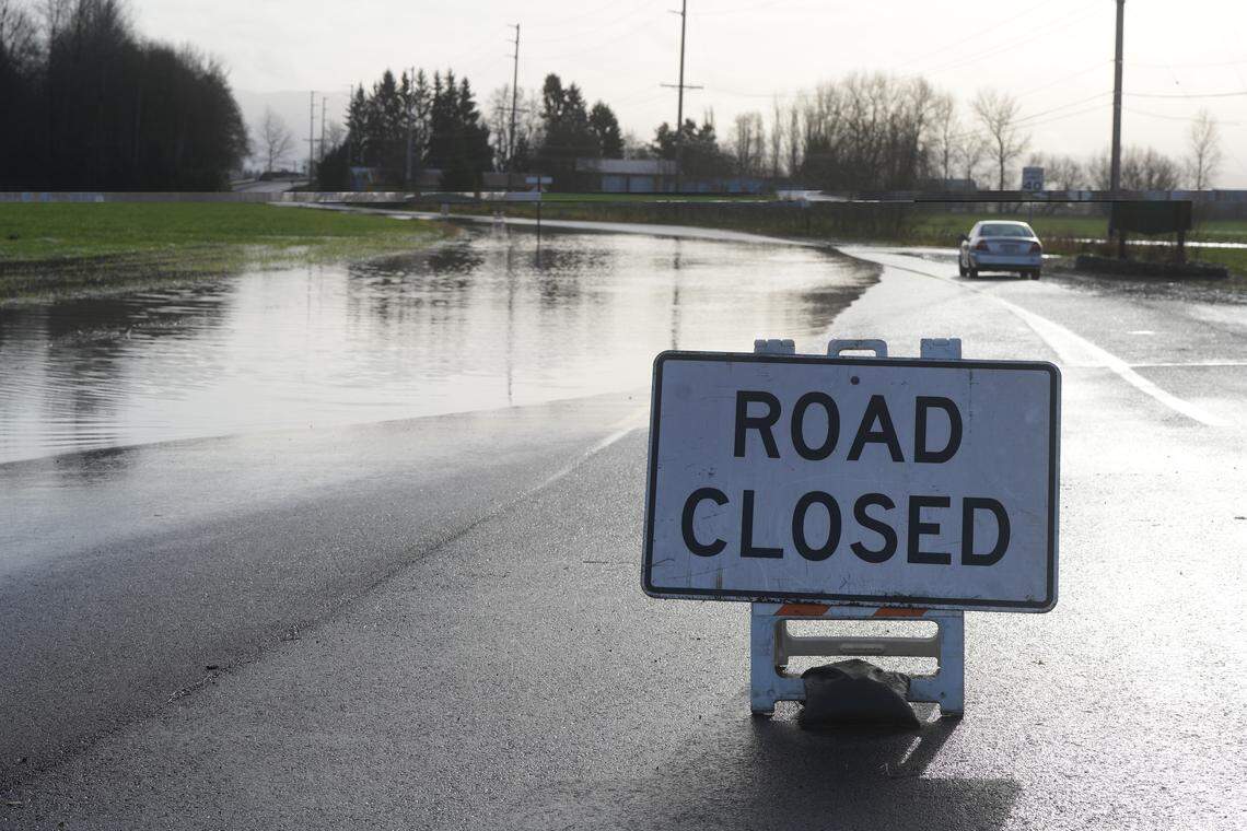 A sign indicates the closure of Hannegan Road on December 9, 2025, due to flooding over the roadway near Lynden, Wash.