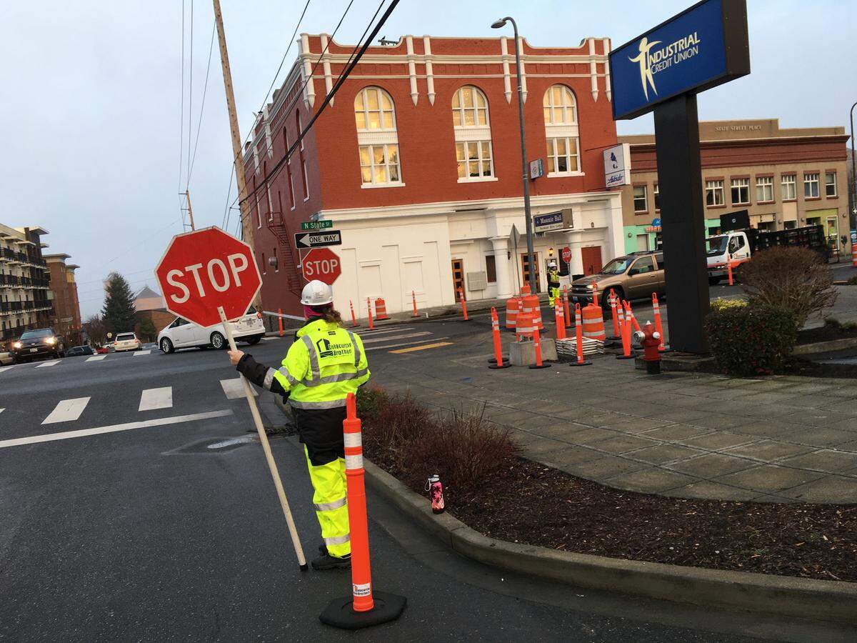 A construction flagger stops traffic at the corner of Maple and State streets near downtown Bellingham in mid-February. New traffic signals are being installed to make the intersection safer for bicyclists and pedestrians.
