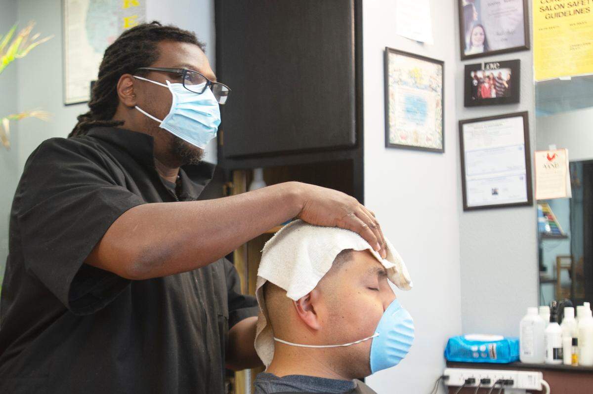Bernard Franklin, the owner of busy B’s Barbershop and Salon, finishes cutting a customer’s hair on Monday, July 12, in Bellingham.