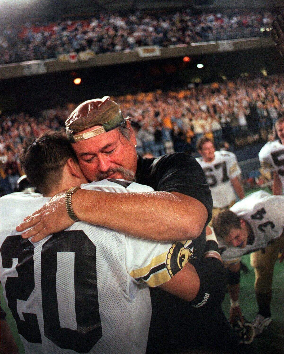 Head coach Bob Ames hugs Joel Pears following the Trojans’ victory over East Valley to capture the 2A championship Saturday, Dec. 4, 1999, at the Tacoma Dome.