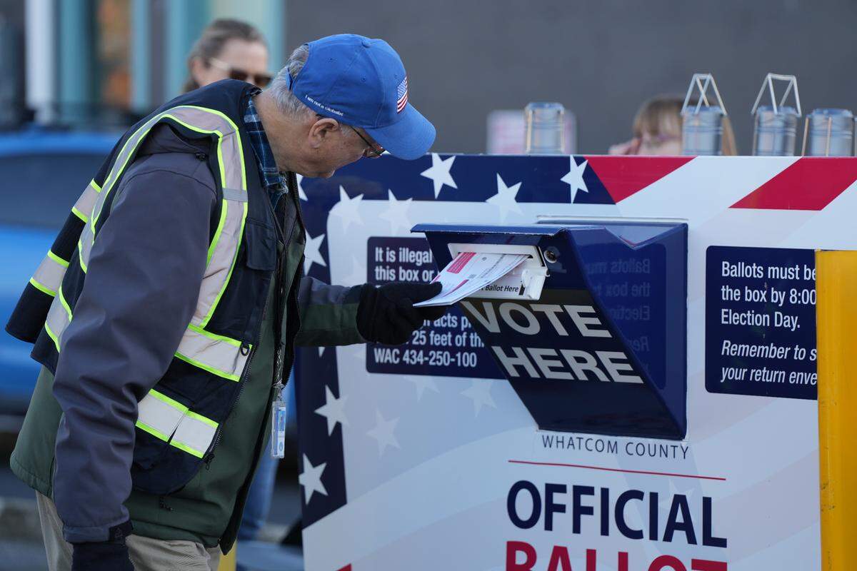 A volunteer helps people cast their ballots at a drive-up ballot drop box on November 5, 2024, in Bellingham, Wash.