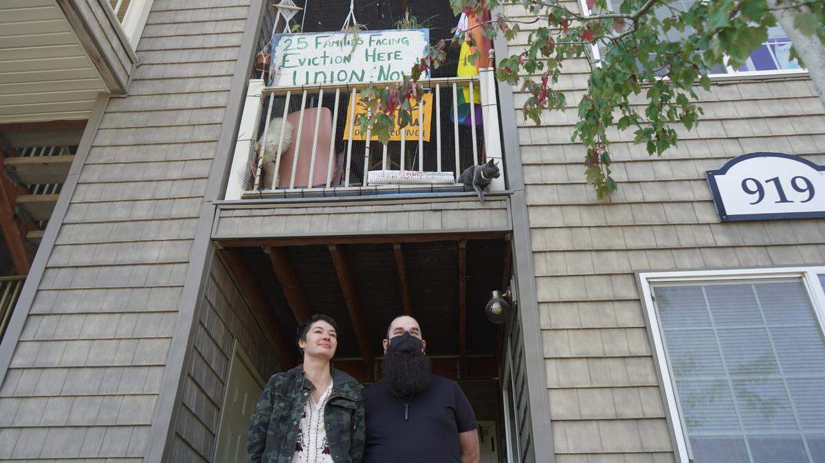 Michi Marcher, left, and Cináed Boyd stand in front of their residence at the Meadow Wood Townhomes on Sept. 22, 2023, in Bellingham, Wash. Marcher and Boyd are working to unionize the tenants at the complex. Tenants want the current property manager to be removed from their position and for ongoing habitability issues to be addressed.