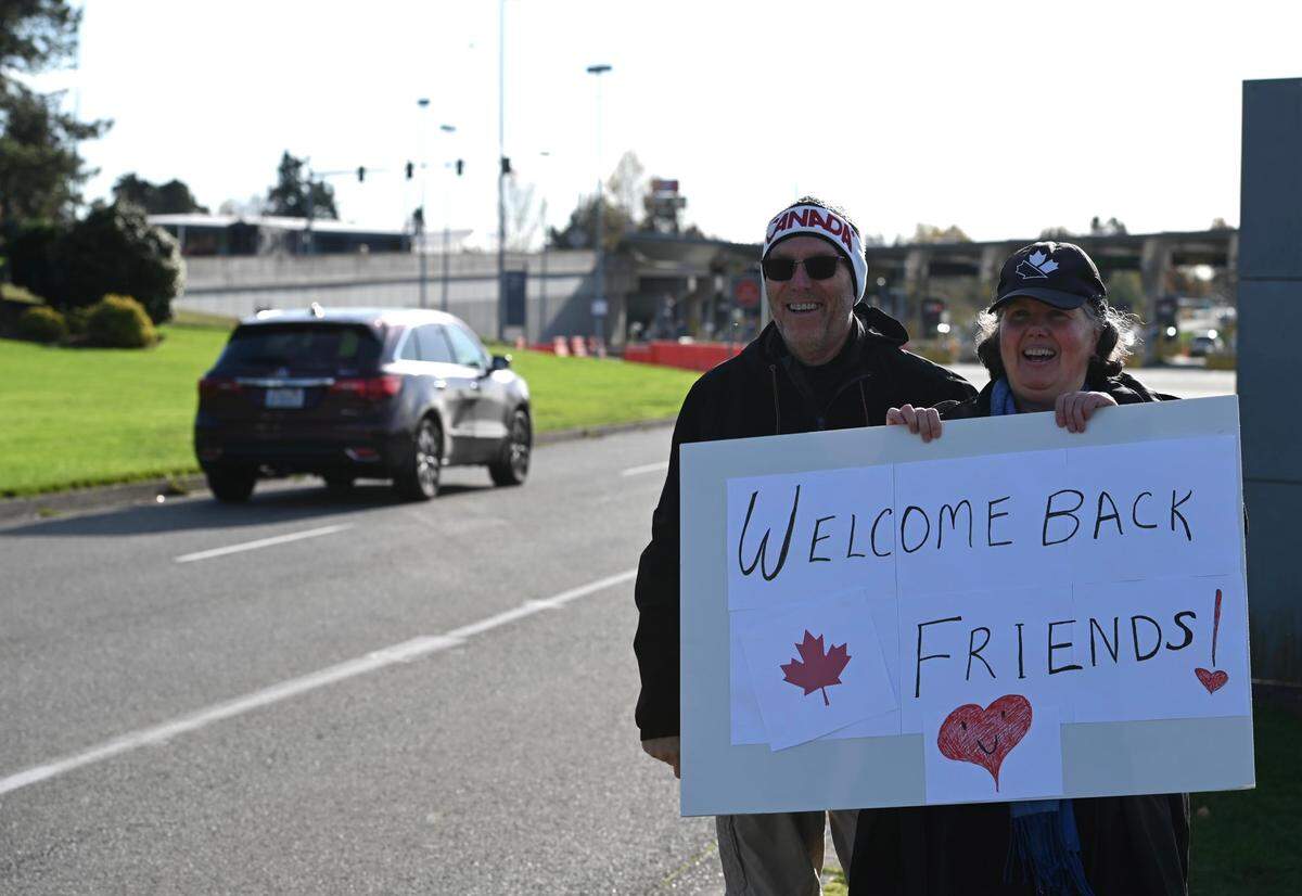 Blaine resident and dual citizen Traysi Spring, right, and her husband, Tom Bakken, greet Canadians near the Peace Arch border crossing Monday, Nov. 8, in Blaine. The U.S. reopened its border to vaccinated Canadians traveling for “non-essential” reasons, such as shopping or tourism, after nearly 600 days of restricted travel due to the COVID-19 pandemic.