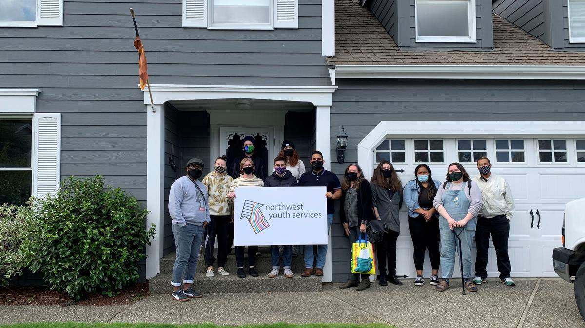 Members of the Northwest Youth Services staff pose with the Samish neighborhood home they bought for a youth shelter as the deal closed Thursday, Sept. 30, in Bellingham.