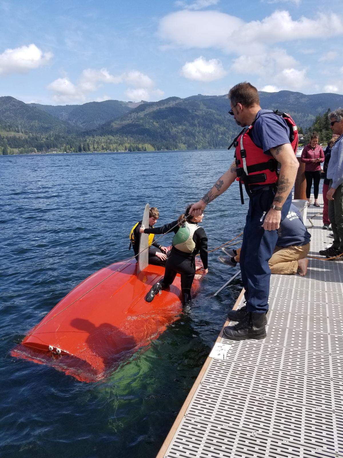 South Whatcom Fire Lt. Scott Crowe and other boaters help pull a sailboat to the dock at Western Washington University’s Lakewood water sports facility on Lake Whatcom on April 26, 2019. SWFA crews rescued the sailor, who became entangled in the rigging after his boat capsized.