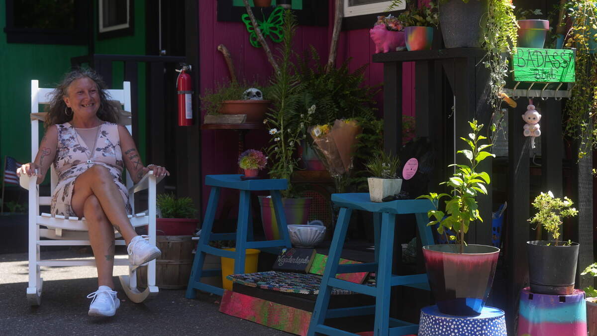 Desiree Rodriguez sits in a rocking chair in front of her unit at the North Haven tiny home village in Bellingham.
