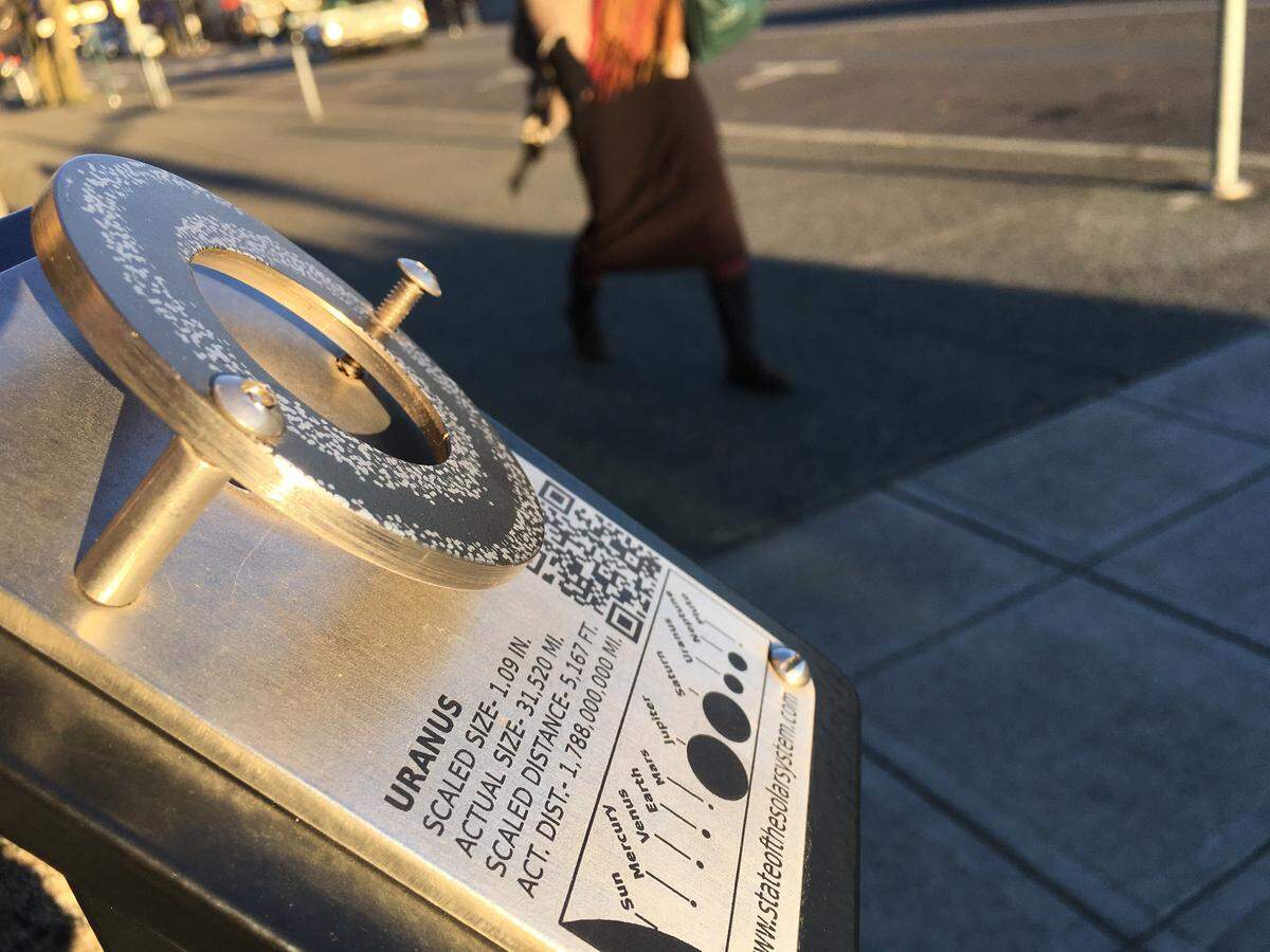 A pedestrian walks past the empty “State of the Solar System” display for the planet Uranus on Monday morning. Nine marbles from the State Street installation were reported stolen Friday.