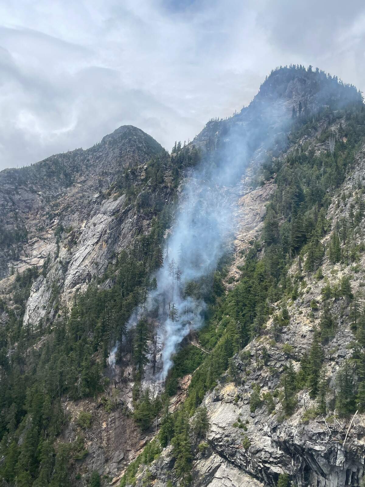 A wildfire called the Luna Fire is shown July 2, 2026, burning in steep and rocky terrain west of Ross Lake in southeast Whatcom County, Wash.