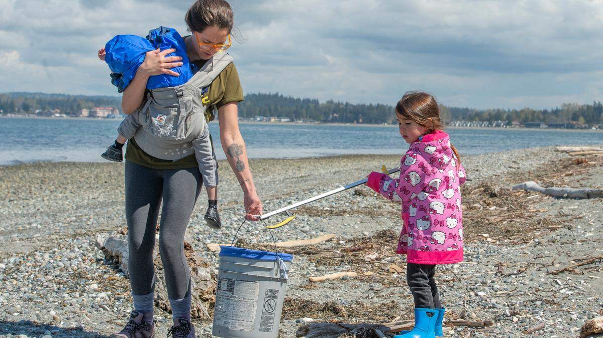 Kassy Stuart helps her daughter Kadence Stuart, 4, as they pick up trash at a beach cleanup organized by Re Sources and the Surfrider Foundation for Earth Day on Friday, April 22, 2022, at Birch Bay State Park in Blaine, Wash.