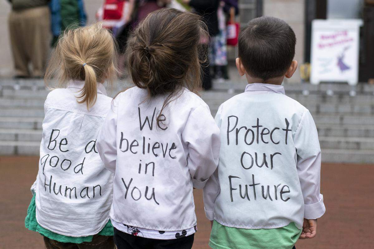 Three young children stand at the front of a climate action rally outside of Bellingham City Hall Friday.