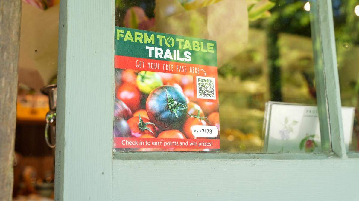A business displays a 2026 Farm to Table Trails decal. People can earn points by checking in at locations along nine curated trails using an online pass.