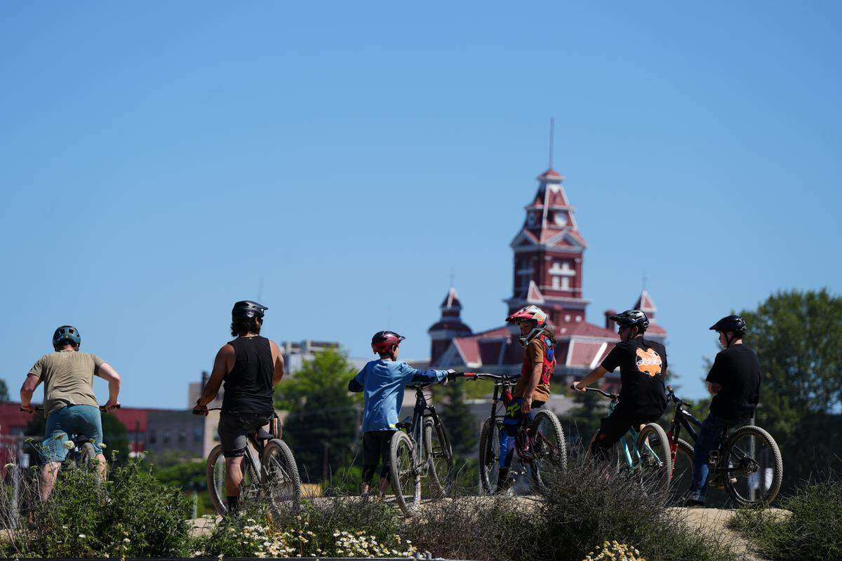 Youth and adult mountain bikers stand at the top of a jump line at the third annual Northwest Tune-Up festival on July 14, 2024, in Bellingham, Wash.