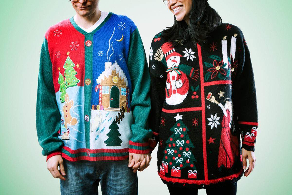 A man and woman wear ugly Christmas sweaters.
