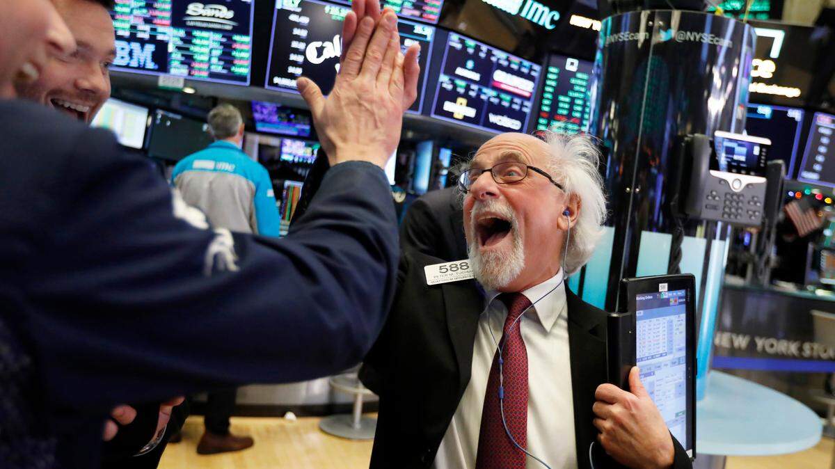 Traders Peter Tuchman, right, slaps a high five before the closing bell on the floor of the New York Stock Exchange, Wednesday. The Dow closed up more than 1,000 points in best day for Wall Street in 10 years as stocks rally back from Christmas Eve beating.