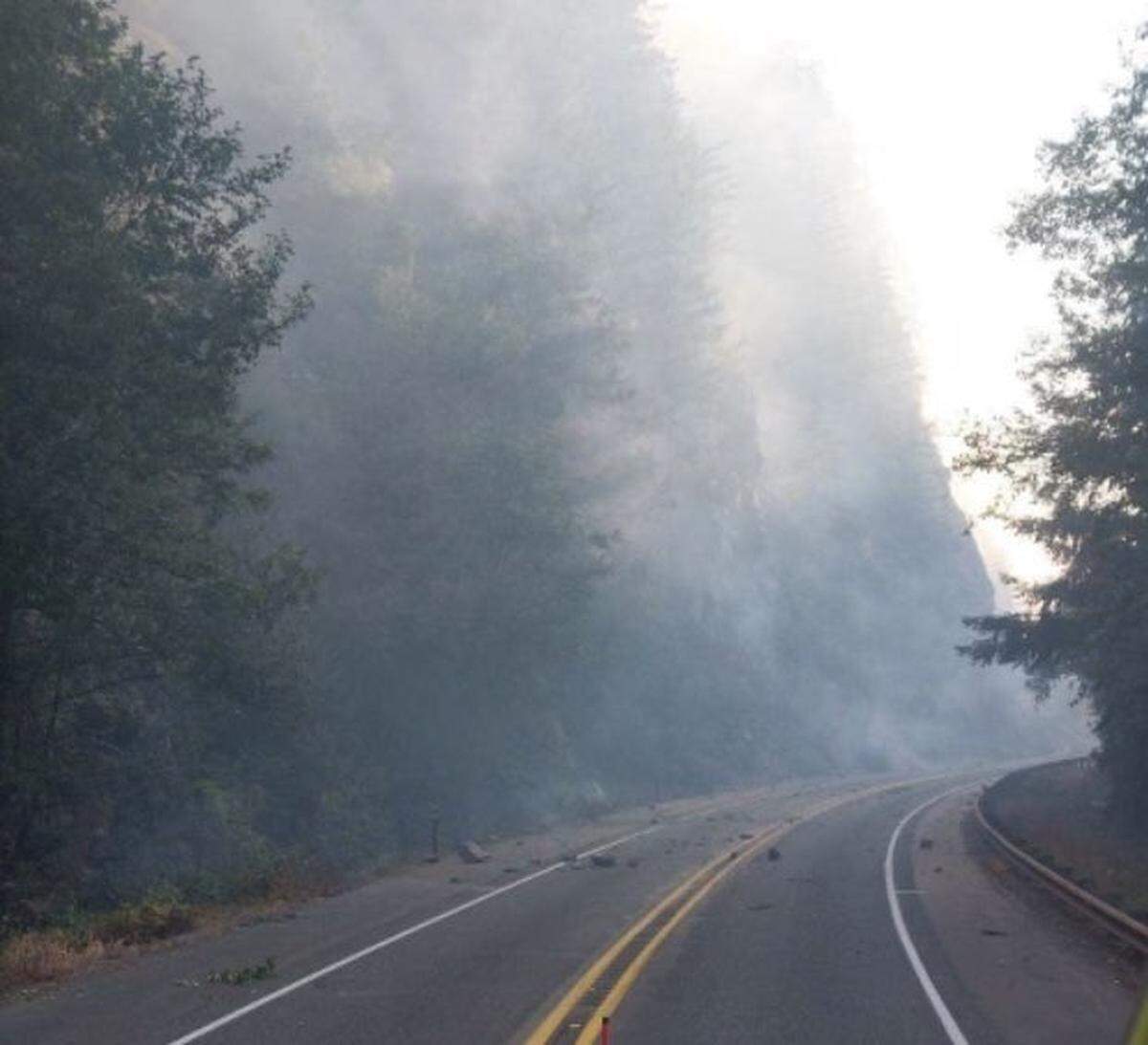 Wildfire smoke hangs in the air as rocks tumble onto Highway 20 near Newhalem, Wash., in Whatcom County on Friday, Aug. 12, 2023