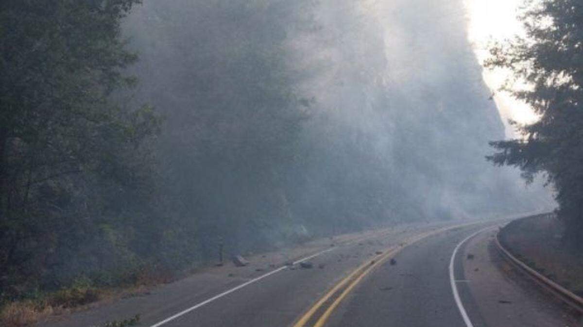 Wildfire smoke hangs in the air as rocks tumble onto Highway 20 near Newhalem, Wash., in Whatcom County on Friday, Aug. 12, 2023
