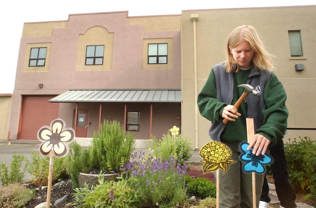 A Bellingham Parks and Recreation Department employee hammers decorative flowers on posts into place in the herb garden behind the Whatcom Museum of History and Art in 2002. Mayor Kelli Linville said that good pay and benefits attract quality employees to the city.