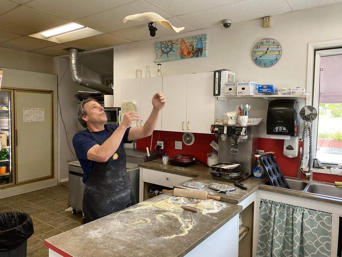 Chuck Laird, co-owner of a Shell station in Point Roberts, makes pizza for a resident on Thursday, June 10. Local businesses of all kinds have suffered as a result of the border shutdown.