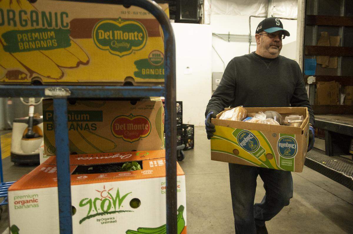 Bill Pearsall, a warehouse assistant and truck driver, unloads boxes of perishable foods from a truck at the Bellingham Food Bank in 2019.