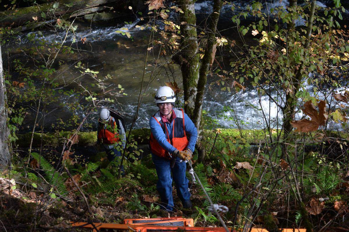 Antea Group workers climb up the embankment along Whatcom Creek in 2013, after looking for water seeping from the hillside to test for gasoline from the pipeline explosion that happened in 1999 in Whatcom Falls Park.